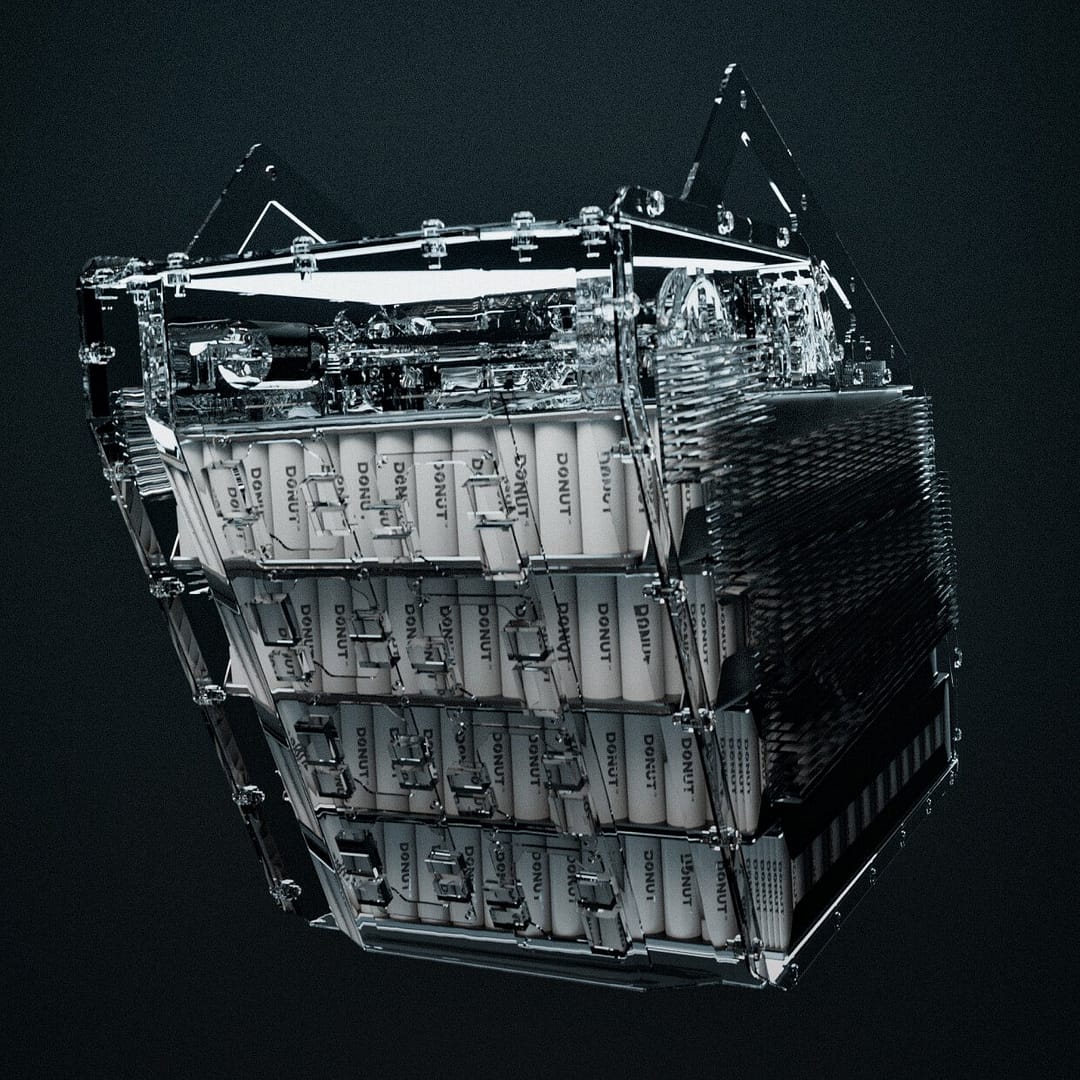 A complex, transparent mechanical cube featuring various intricate components and structures, including labeled panels and wires. The cube is suspended against a dark background, suggesting a technological or futuristic design.